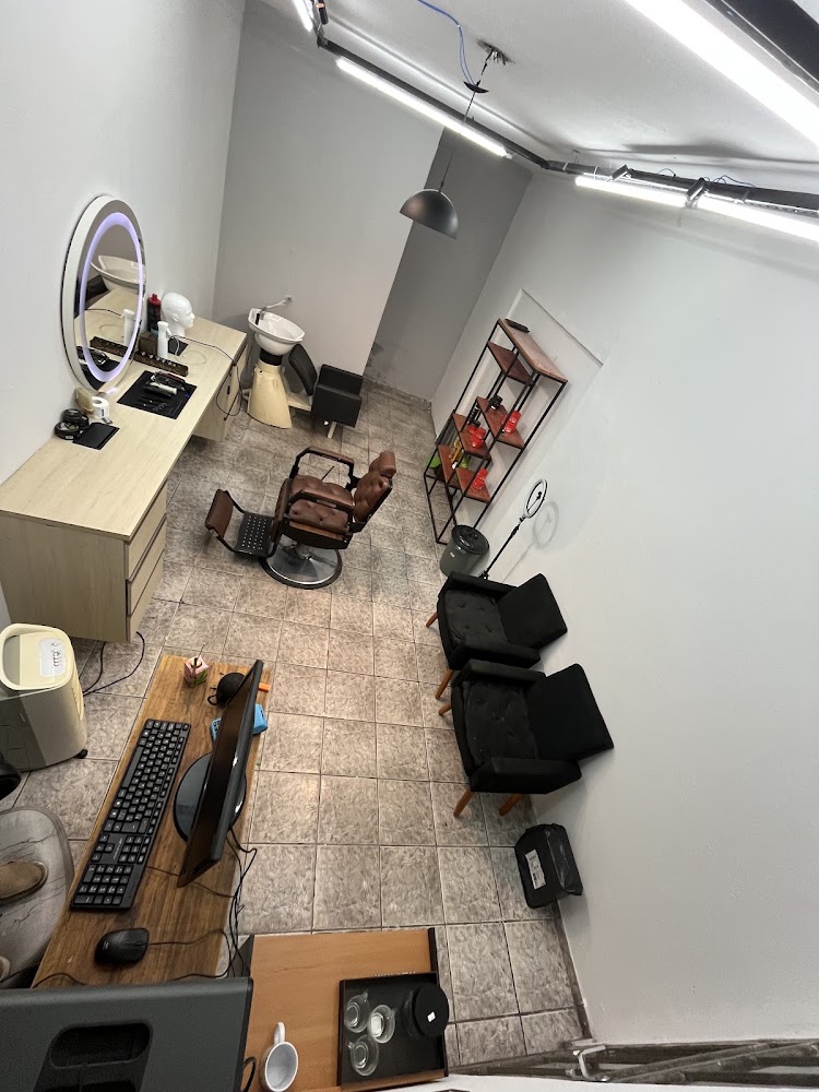 Interior da barbearia com cadeira reclinável, espelho iluminado e poltronas de espera