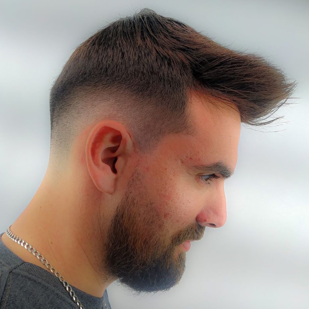 Cliente de perfil com corte degradê e barba alinhada finalizados na barbearia